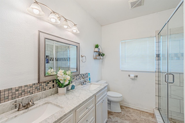 full bathroom featuring a shower stall, toilet, double vanity, and tasteful backsplash