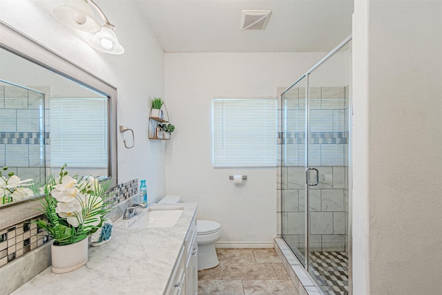 bathroom with toilet, vanity, a stall shower, and baseboards