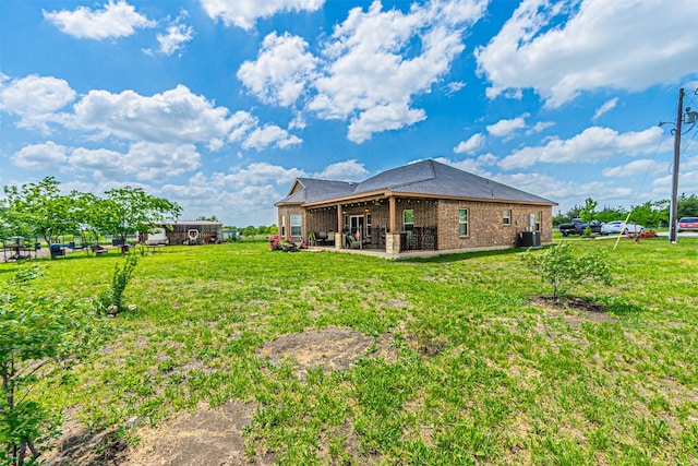rear view of house featuring a patio, brick siding, central AC unit, and a yard
