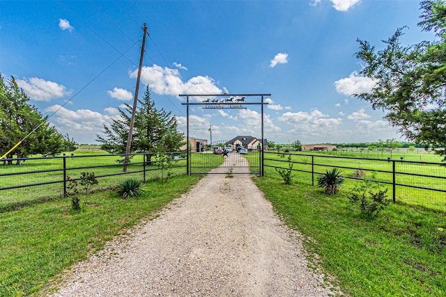 view of dirt / gravel road with a gate, a view of countryside, and a gated entry