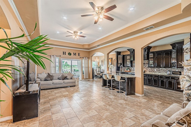 living room with ceiling fan, ornamental molding, recessed lighting, arched walkways, and a tray ceiling
