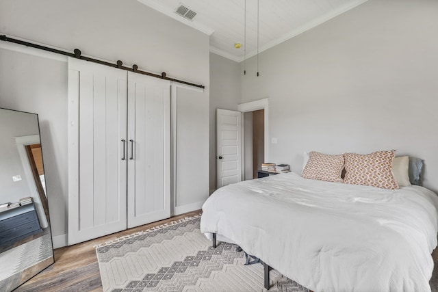 608 N Belknap, Stephenville, TX 76401 - bedroom featuring a barn door, crown molding, wood finished floors, baseboards, and a high ceiling