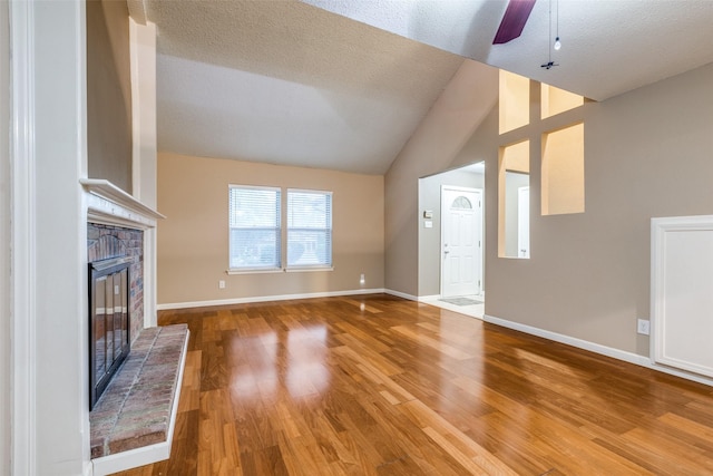 410 Lone Oak Cir, Euless, TX 76039 - unfurnished living room featuring a glass covered fireplace, wood finished floors, ceiling fan, baseboards, and lofted ceiling
