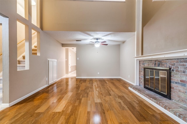 410 Lone Oak Cir, Euless, TX 76039 - unfurnished living room featuring wood finished floors, a ceiling fan, a fireplace, baseboards, and a textured ceiling
