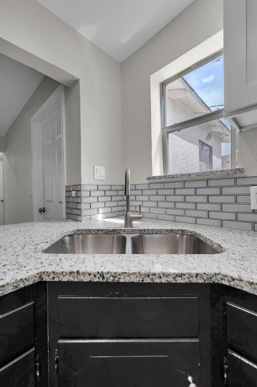 2709 Sarah St, Waco, TX 76706 - kitchen featuring a sink, backsplash, and dark cabinetry