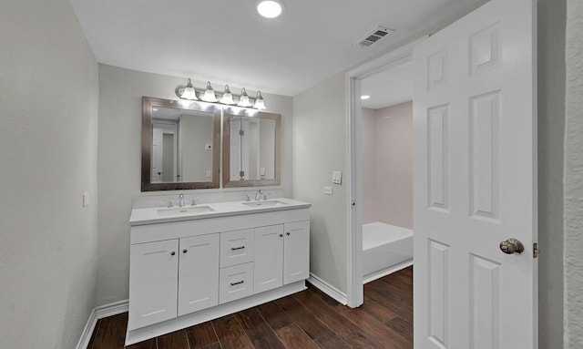 2709 Sarah St, Waco, TX 76706 - bathroom featuring baseboards, wood finished floors, double vanity, a tub, and recessed lighting