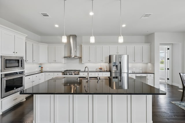 kitchen with stainless steel appliances, wall chimney range hood, dark countertops, white cabinetry, and recessed lighting