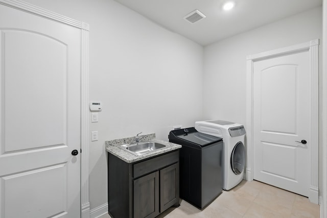 laundry area featuring washing machine and clothes dryer, cabinet space, and light tile patterned floors