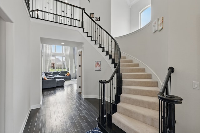 stairs featuring plenty of natural light, baseboards, hardwood / wood-style floors, and a towering ceiling