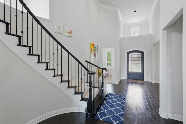 entryway with a high ceiling, hardwood / wood-style flooring, stairway, baseboards, and ornamental molding
