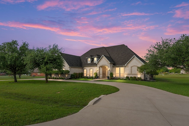 11109 Brook Green Ln, Haslet, TX 76052 - french country inspired facade featuring curved driveway, brick siding, a yard, and roof with shingles