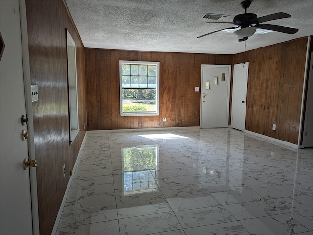11728 Fm 1399, Marietta, TX 75566 - foyer entrance with light marble finish floors, wooden walls, a ceiling fan, a textured ceiling, and baseboards