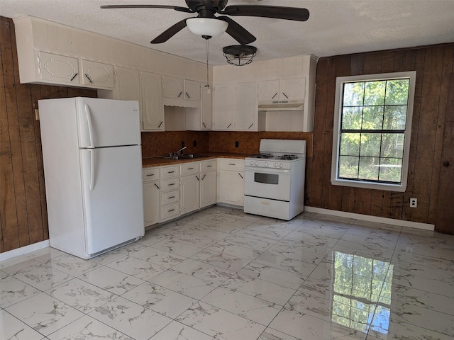 11728 Fm 1399, Marietta, TX 75566 - kitchen featuring white appliances, wooden walls, baseboards, light marble finish flooring, and a textured ceiling