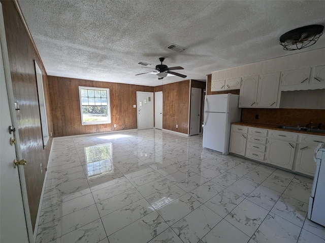 11728 Fm 1399, Marietta, TX 75566 - kitchen with freestanding refrigerator, wooden walls, light marble finish flooring, a ceiling fan, and a sink