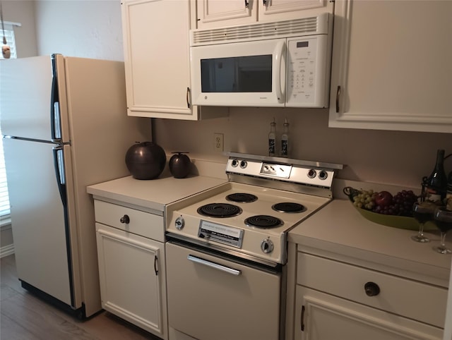 539 W Lookout Dr Unit 135, Richardson, TX 75080 - kitchen featuring electric stove, white microwave, freestanding refrigerator, light countertops, and white cabinetry