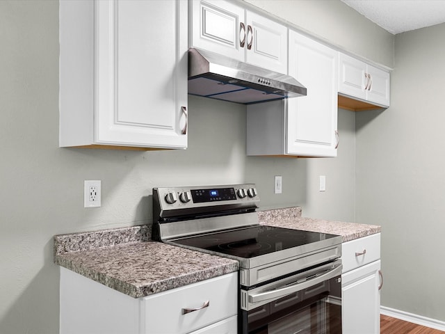 4704 Kristie Dr, Balch Springs, TX 75180 - kitchen featuring stainless steel range with electric stovetop, under cabinet range hood, white cabinets, wood finished floors, and baseboards