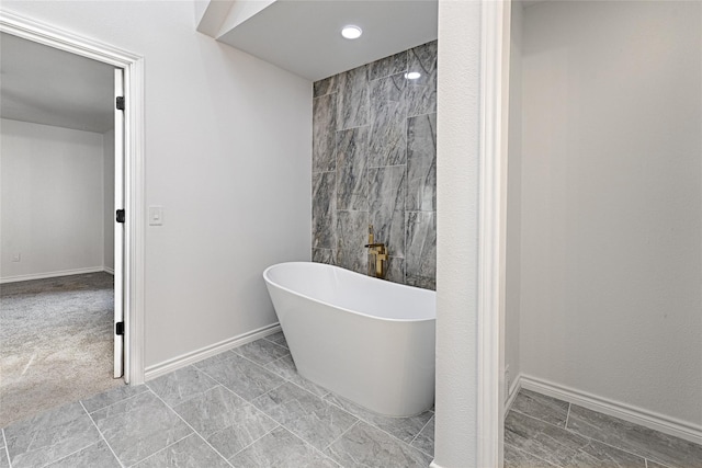 bathroom with a freestanding tub, baseboards, and recessed lighting