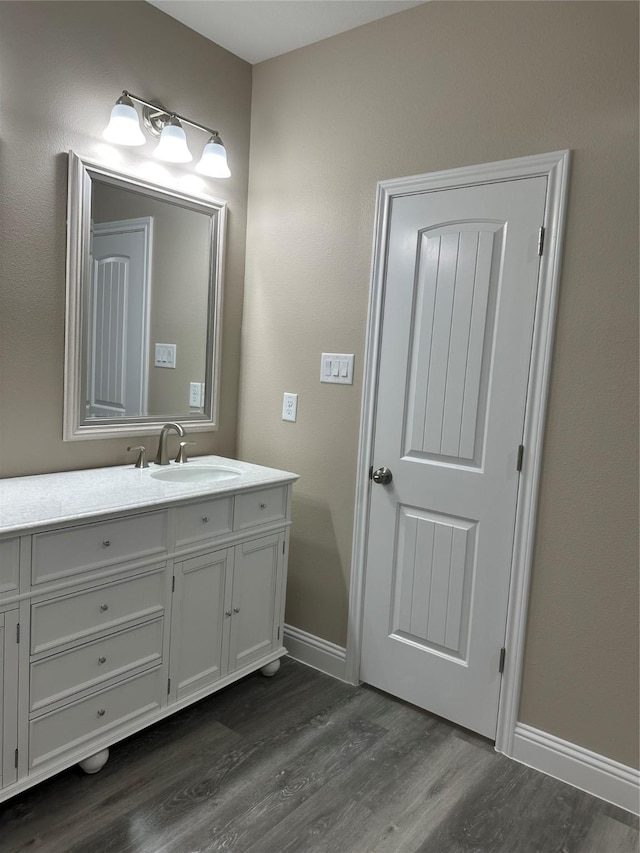 1009 S Preston St, Ennis, TX 75119 - bathroom featuring wood finished floors, baseboards, and vanity