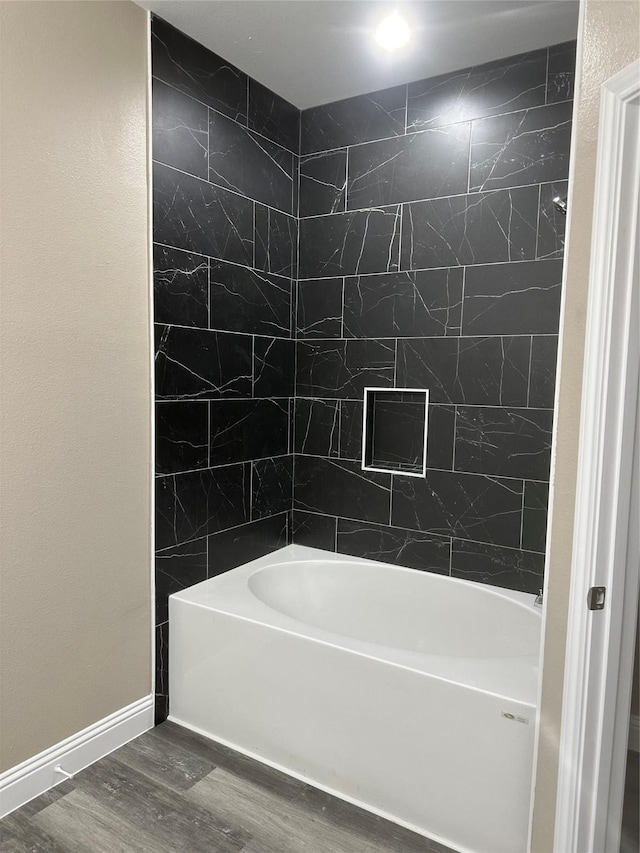 1009 S Preston St, Ennis, TX 75119 - full bathroom with wood finished floors, bathtub / shower combination, and baseboards