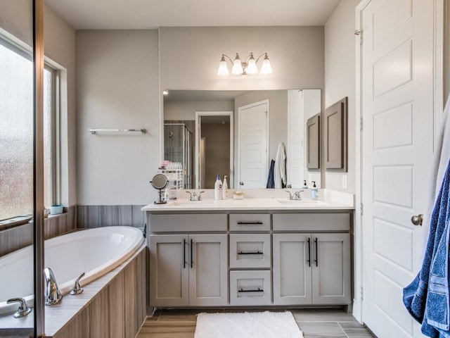 bathroom featuring plenty of natural light, double vanity, a shower stall, and a bath