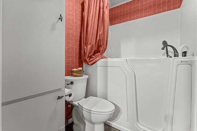 full bath with tile walls, toilet, a tub to relax in, and curtained shower