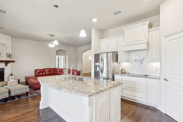 kitchen with a sink, stainless steel fridge, open floor plan, arched walkways, and recessed lighting