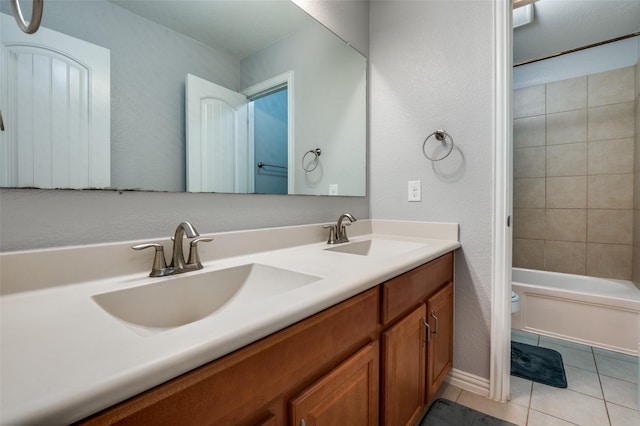 bathroom featuring tile patterned flooring, double vanity, toilet, shower / washtub combination, and a textured wall