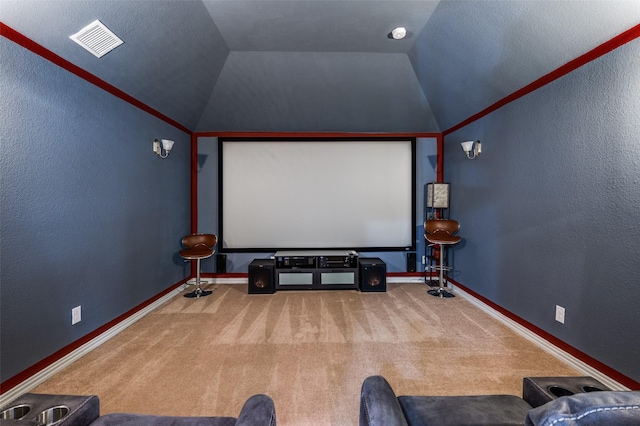 carpeted cinema room featuring lofted ceiling, baseboards, and a textured wall