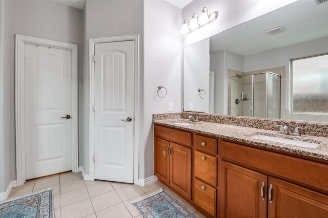 bathroom with tile patterned flooring, a stall shower, double vanity, and baseboards