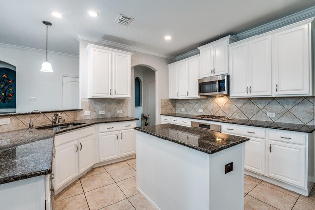 kitchen with stainless steel appliances, arched walkways, a sink, ornamental molding, and white cabinetry