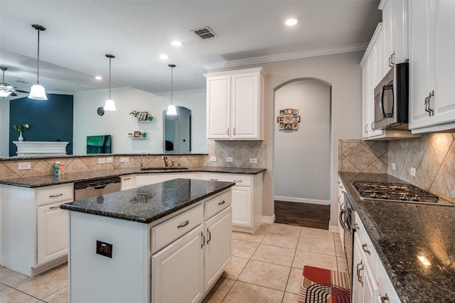 kitchen featuring appliances with stainless steel finishes, a sink, arched walkways, a peninsula, and ceiling fan