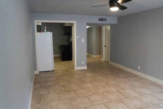 empty room with a ceiling fan, a textured ceiling, and light tile patterned floors