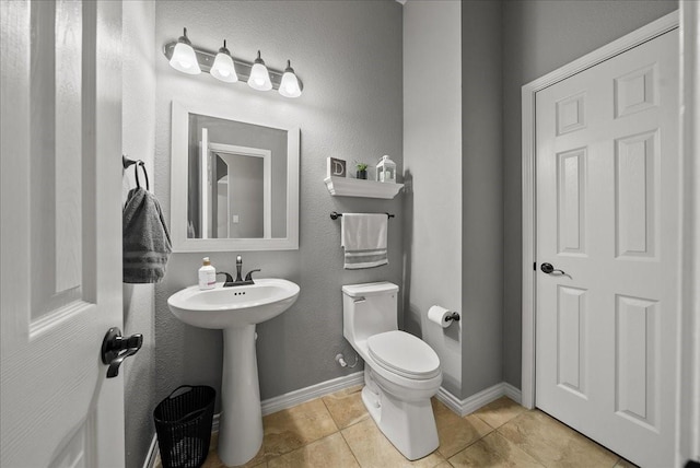 half bathroom featuring tile patterned flooring, toilet, and a sink