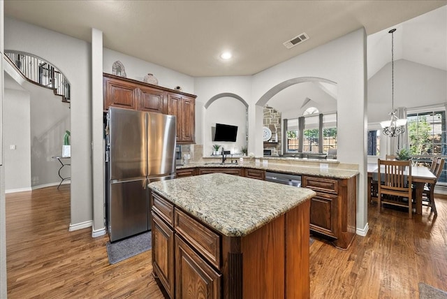 kitchen featuring appliances with stainless steel finishes, a kitchen island, dark wood-style flooring, light stone countertops, and plenty of natural light