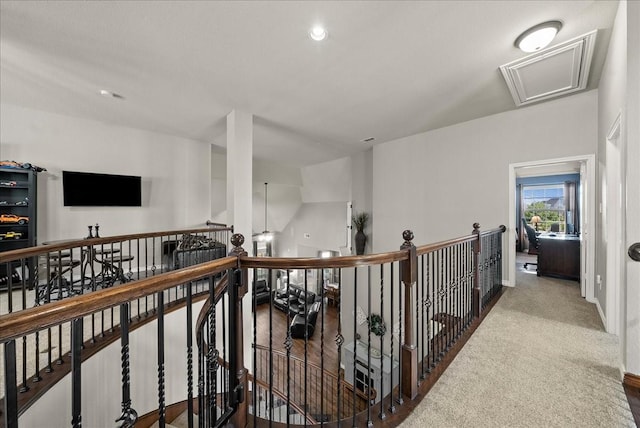 hall featuring an upstairs landing, baseboards, and attic access
