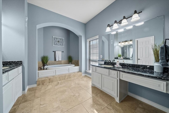 full bath with vanity, a bath, and baseboards