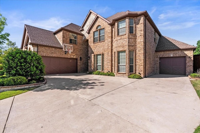 traditional home with brick siding, concrete driveway, a garage, and a shingled roof
