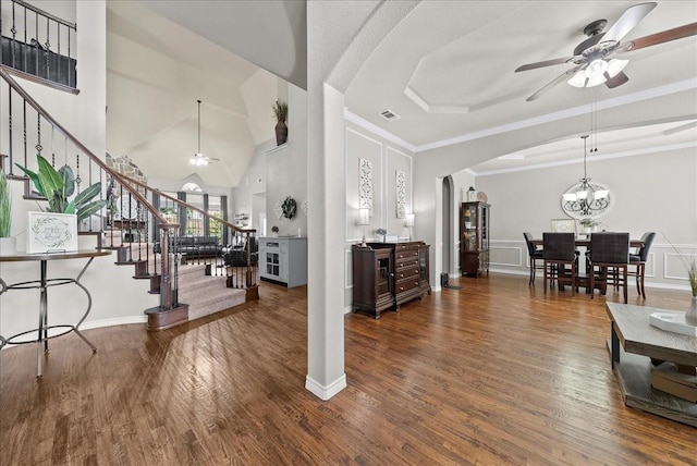 living room with a ceiling fan, arched walkways, stairs, wood finished floors, and ornamental molding