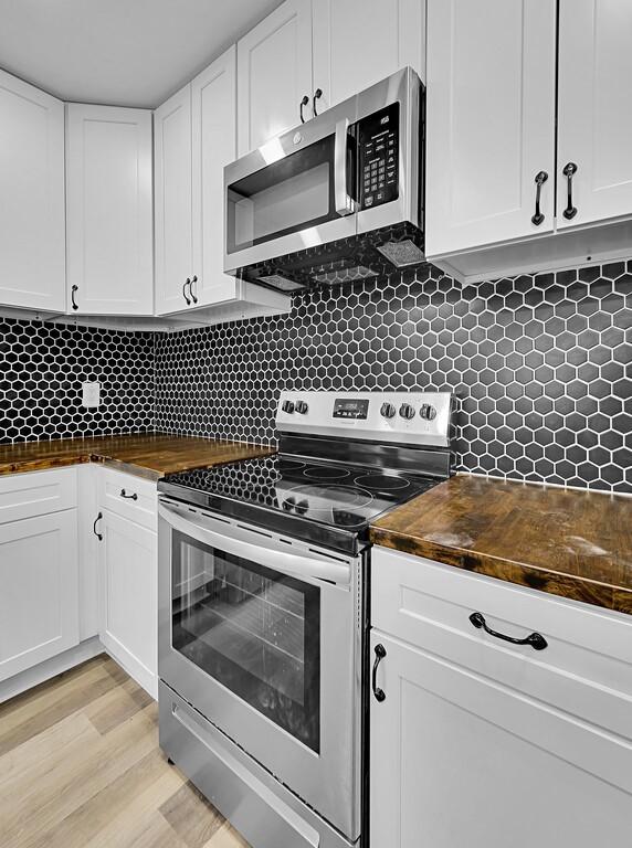1713 Reuter Ave, Waco, TX 76708 - kitchen with appliances with stainless steel finishes, wood counters, white cabinets, and tasteful backsplash