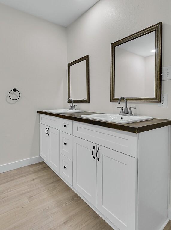 1713 Reuter Ave, Waco, TX 76708 - full bath with wood finished floors, double vanity, and baseboards