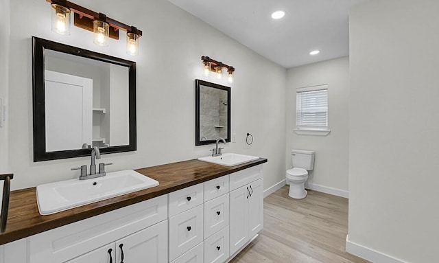 1713 Reuter Ave, Waco, TX 76708 - bathroom featuring toilet, baseboards, wood finished floors, recessed lighting, and double vanity