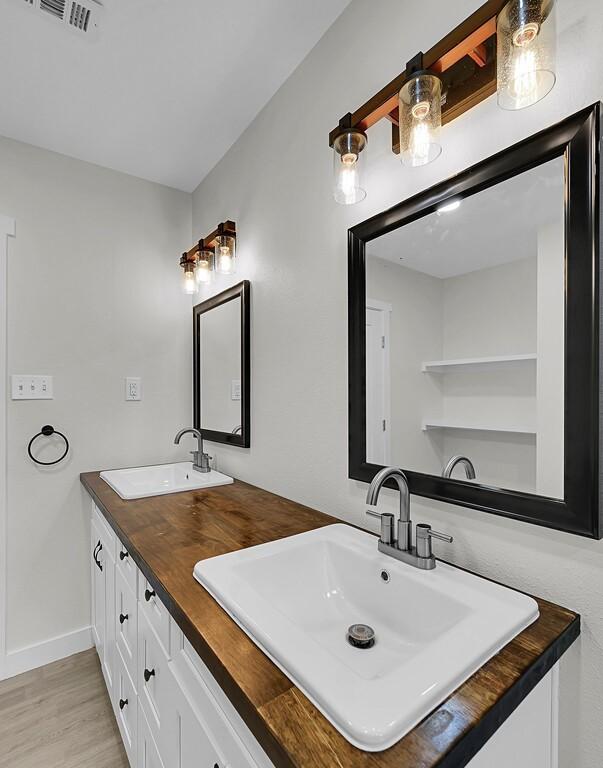1713 Reuter Ave, Waco, TX 76708 - full bath with double vanity, wood finished floors, and baseboards