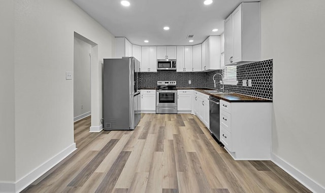 1713 Reuter Ave, Waco, TX 76708 - kitchen with stainless steel appliances, dark countertops, a sink, light wood-style flooring, and decorative backsplash