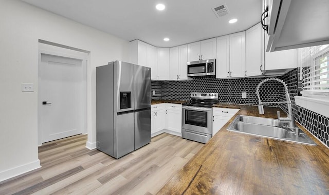1713 Reuter Ave, Waco, TX 76708 - kitchen featuring stainless steel appliances, a sink, backsplash, white cabinetry, and light wood-style flooring