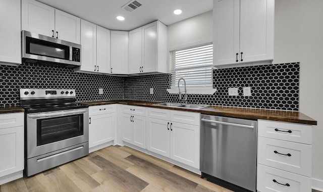 1713 Reuter Ave, Waco, TX 76708 - kitchen with stainless steel appliances, a sink, wooden counters, white cabinetry, and backsplash