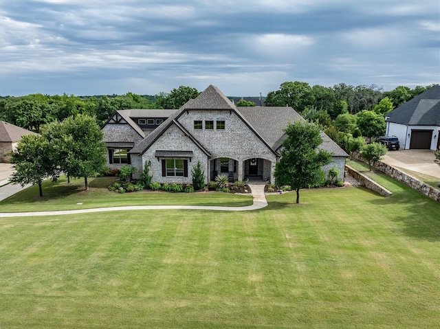 french country inspired facade featuring stone siding, a front lawn, a shingled roof, and brick siding