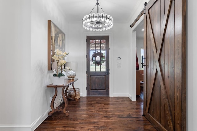 foyer entrance featuring a barn door, wood finished floors, baseboards, a chandelier, and crown molding