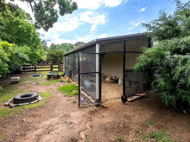 view of outdoor structure with an outdoor fire pit, an outbuilding, and fence