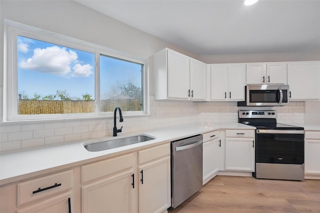 3169 Longbow Dr, Grand Prairie, TX 75052 - kitchen featuring appliances with stainless steel finishes, a sink, decorative backsplash, light wood finished floors, and light countertops