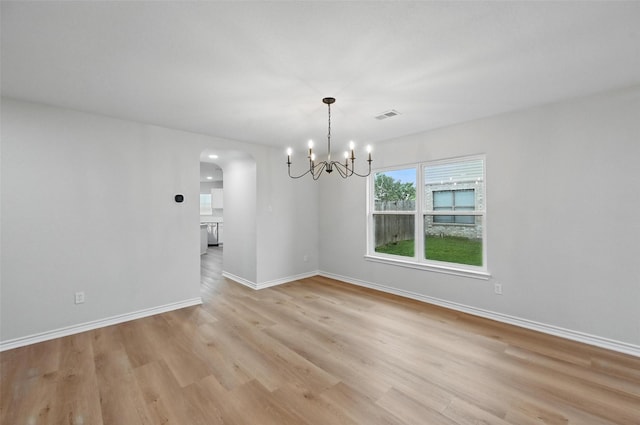 3169 Longbow Dr, Grand Prairie, TX 75052 - unfurnished dining area featuring arched walkways, light wood-style flooring, a chandelier, and baseboards